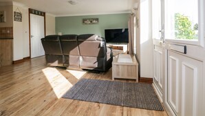 A living room with a sofa, TV, and a small table. - Lower Brambleside (Truro)