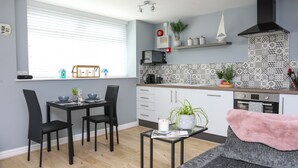 Cozinha moderna com armários brancos, fogão preto e painel de fundo estampado.