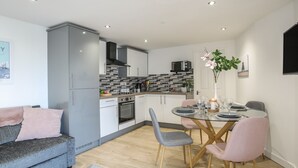 Une cuisine moderne avec des meubles gris, un four à micro-ondes et un dosseret carrelé.