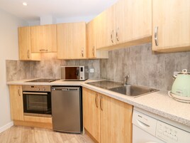 Una cocina moderna con armarios de madera, un lavamanos de acero inoxidable, un microondas, un horno y un lavavajillas.