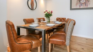 A dining area with a wooden table, leather chairs, and a vase of flowers. - Gairnlea House (Ballater)