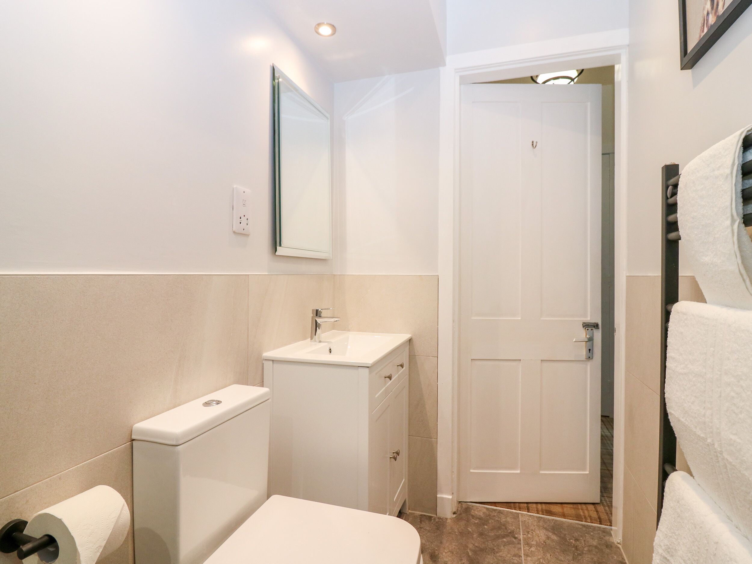 A bathroom with a toilet, sink, and mirror.