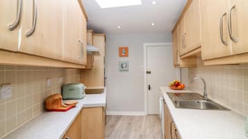 Una cocina compacta con armarios de madera, un tostador y un bol con fruta en la encimera.