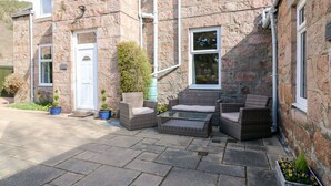 A stone house with a front porch, a door, and a window. - Gairnlea House (Ballater)