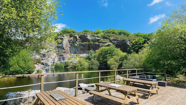 A wooden deck with picnic tables overlooking a body of water and a rocky landscape. - Mellydonen Beder Del , Tor Down Quarry (Bodmin)