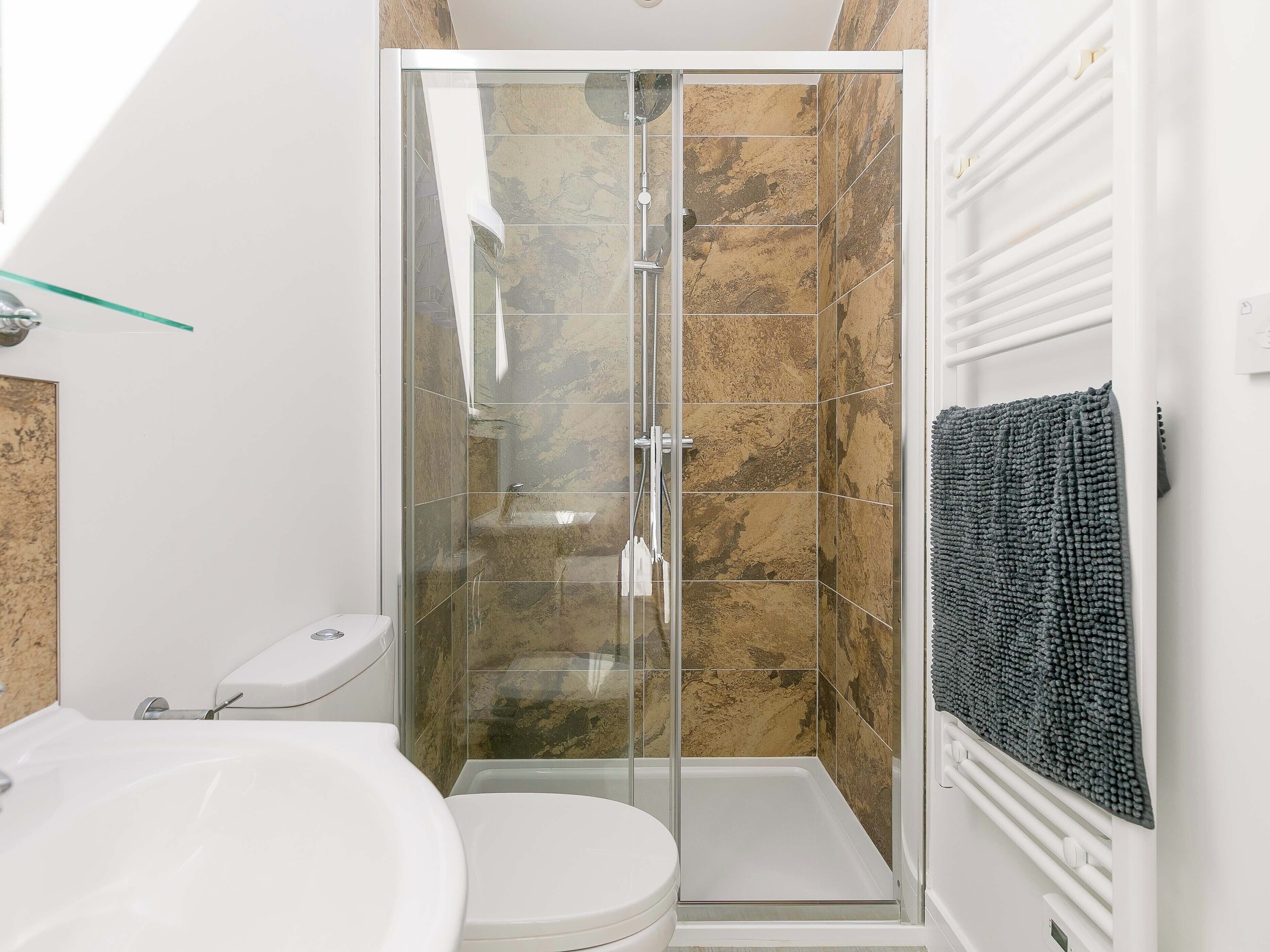 Une salle de bain avec une douche à parois de verre, des toilettes blanches et un lavabo en verre.