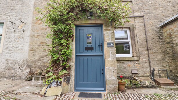 A stone building with a blue door, a small window, and a number plaque.