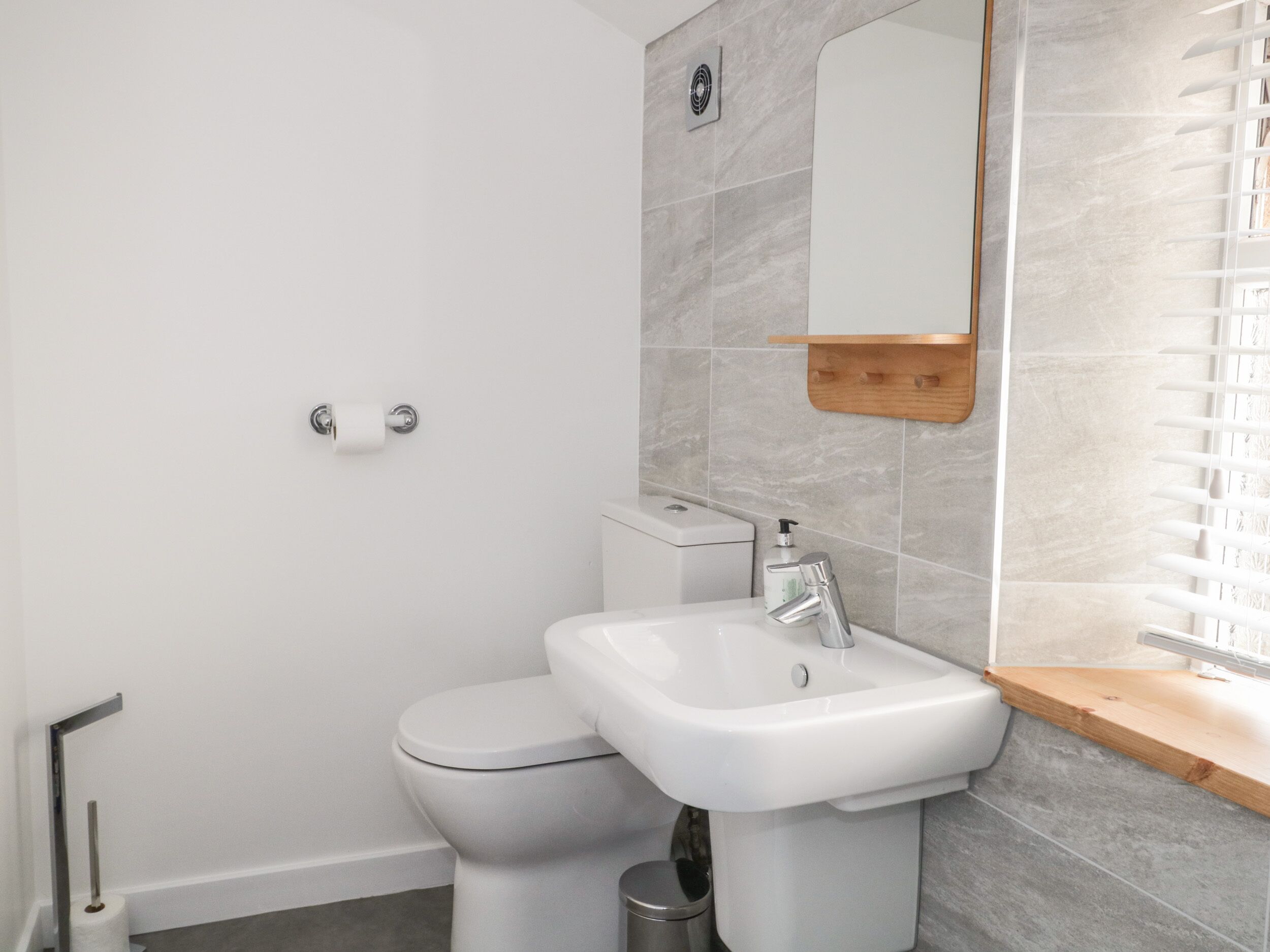 Un baño moderno con inodoro, lavamanos y espejo.