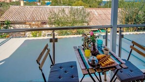 A balcony with a table set for breakfast, overlooking a coastal town and hills. - hara luxury house (Gaios)