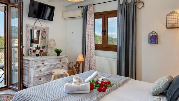 A bedroom with a bed, a dresser, a TV, and a window with curtains. - hara luxury house (Gaios)