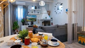 A cozy living room with a dining table set for breakfast, featuring bread, eggs, and juice. - hara luxury house (Gaios)