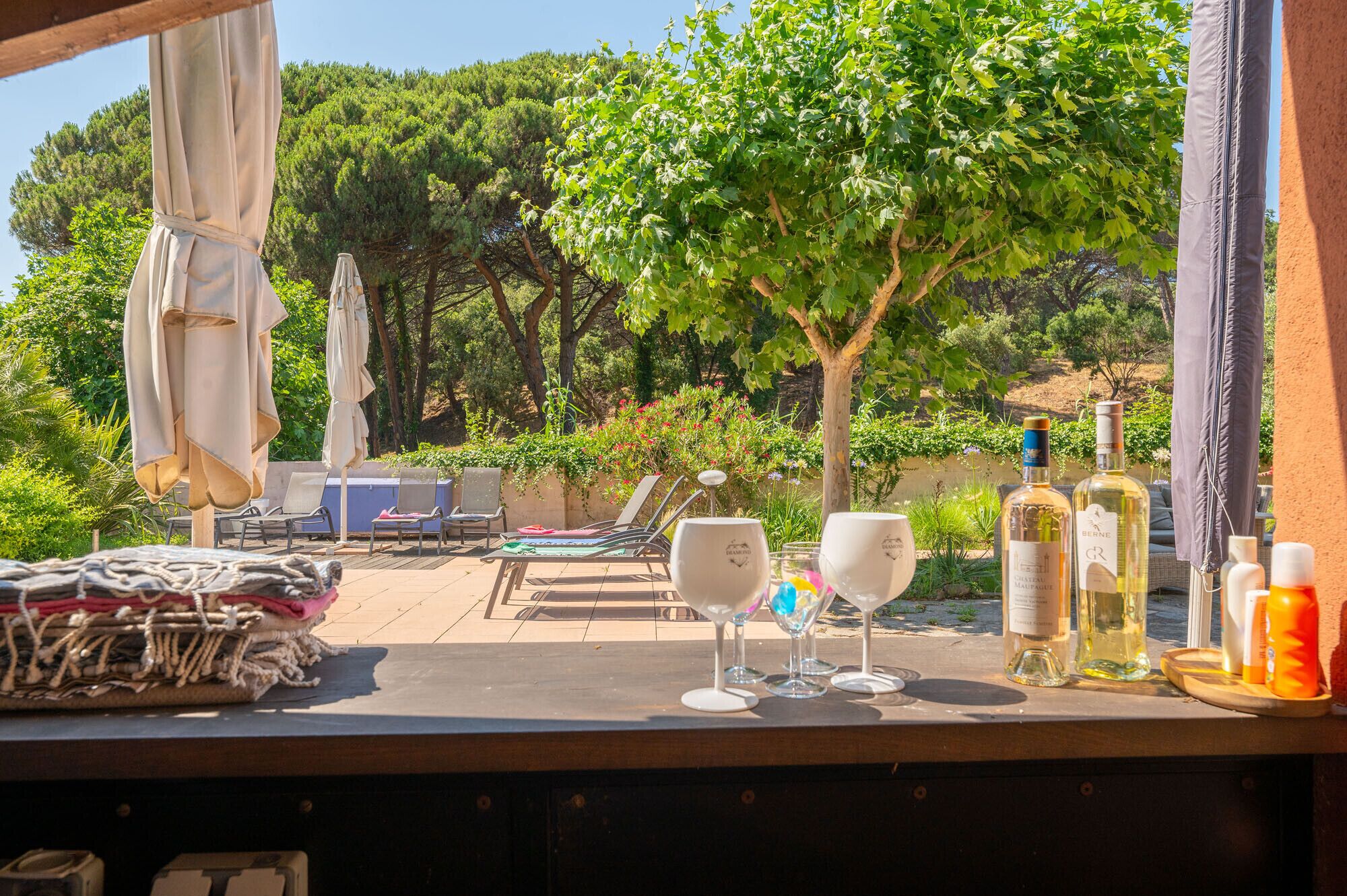 A terrace with outdoor seating, a table with wine glasses and bottles, and a view of a vineyard.
