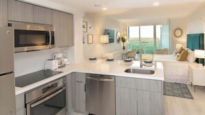 A modern kitchen with stainless steel appliances, a central island with a sink, and a dining area with a view.