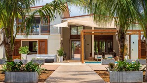 A modern house with a pool, outdoor seating, and potted plants.