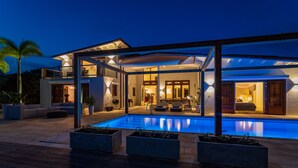 A modern house with a swimming pool, outdoor seating, and a covered patio area.