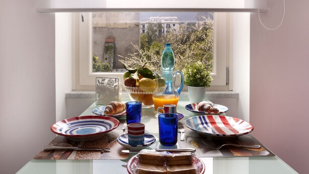 A breakfast table with plates, glasses, a pitcher, and a croissant. - Kira Guest House, apt close to Tasso square (Sorrento)