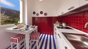 A modern kitchen with a large window, red tiles, and striped stools. - Kira Guest House, apt close to Tasso square (Sorrento)