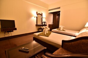 A hotel room with two beds, a TV, a desk, and a mirror. - Simsan Hotel (Chennai)