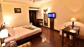 Habitación de hotel con cama, mesita de noche, lámpara, televisor y espejo.