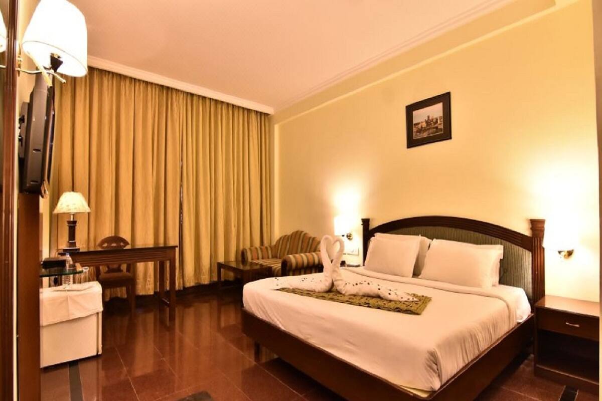 A hotel room with a large bed, a desk, a chair, a television, and a picture on the wall.