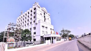 Un hotel de varios pisos con fachada simétrica, entrada central y exhibición de banderas.