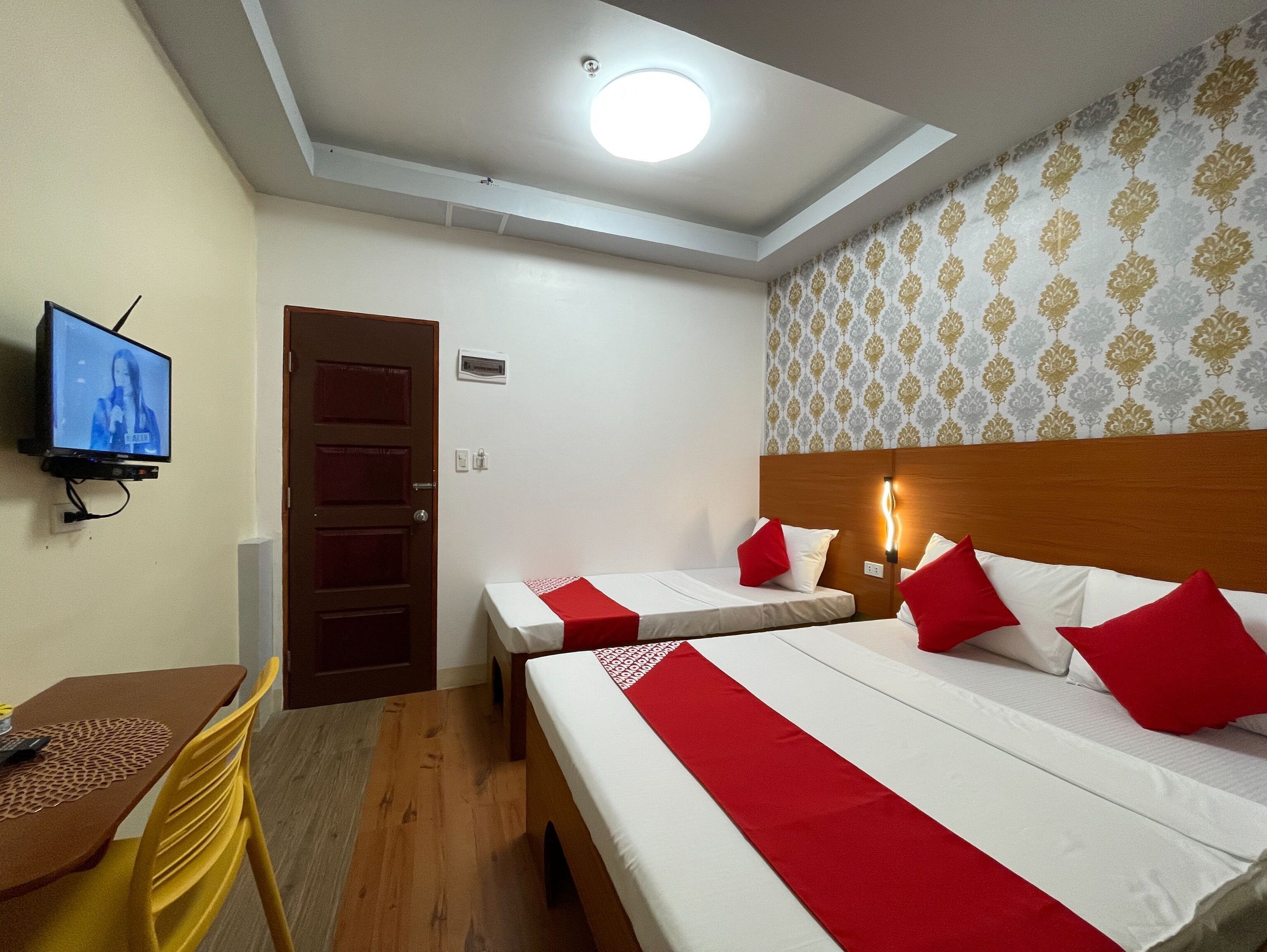 Une chambre d’hôtel avec deux lits, une télévision, un bureau et une chaise.
