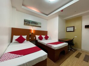 Une chambre d’hôtel avec deux lits simples, un bureau et une chaise.