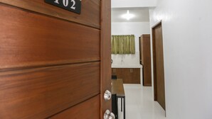 A wooden door with a number plaque, a white tiled floor, a green curtain, and a wooden cabinet. - OYO 736 Jade Apartelle (Cabuyao)