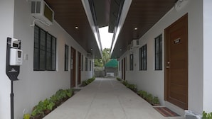 A hallway with potted plants, air conditioning units, and a door labeled "101". - OYO 736 Jade Apartelle (Cabuyao)