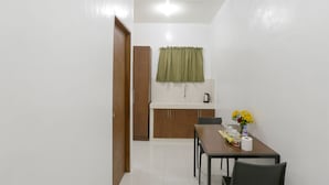 A compact kitchen with a wooden cabinet, a sink, and a window with a green curtain. - OYO 736 Jade Apartelle (Cabuyao)