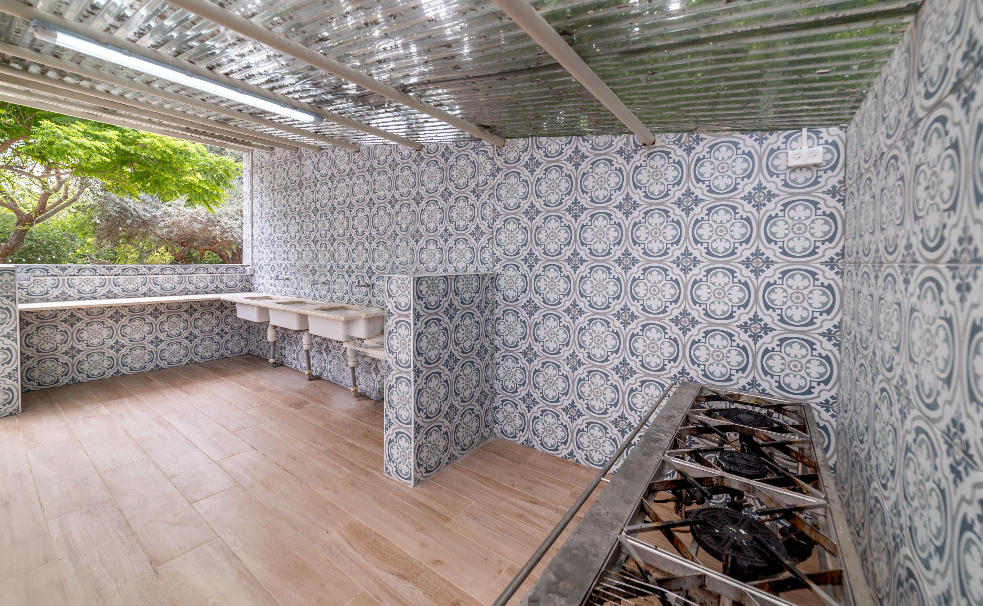 A bathroom with patterned tiles, a wooden floor, and a sink area.