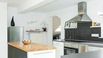 Una cocina moderna con armarios blancos, encimera de madera y campana extractora de acero inoxidable.