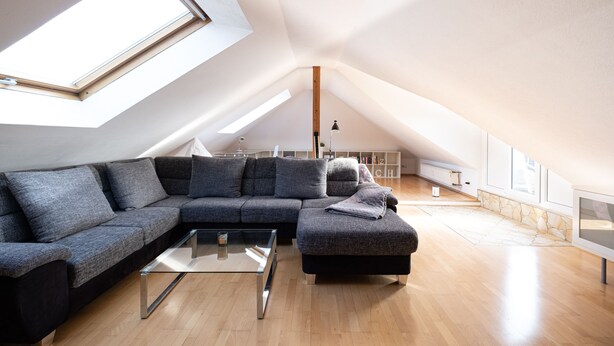 Un appartement moderne de style « loft » doté d’une grande verrière, d’un canapé d’angle, d’une table basse en verre et d’un mur décoratif en pierre.