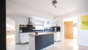 Une cuisine moderne avec des meubles blancs, un îlot central doté d’un plan de travail noir et un pare-feu noir.