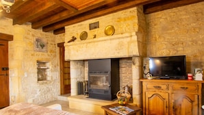 Un intérieur rustique en pierre avec une cheminée, des meubles en bois et un téléviseur.