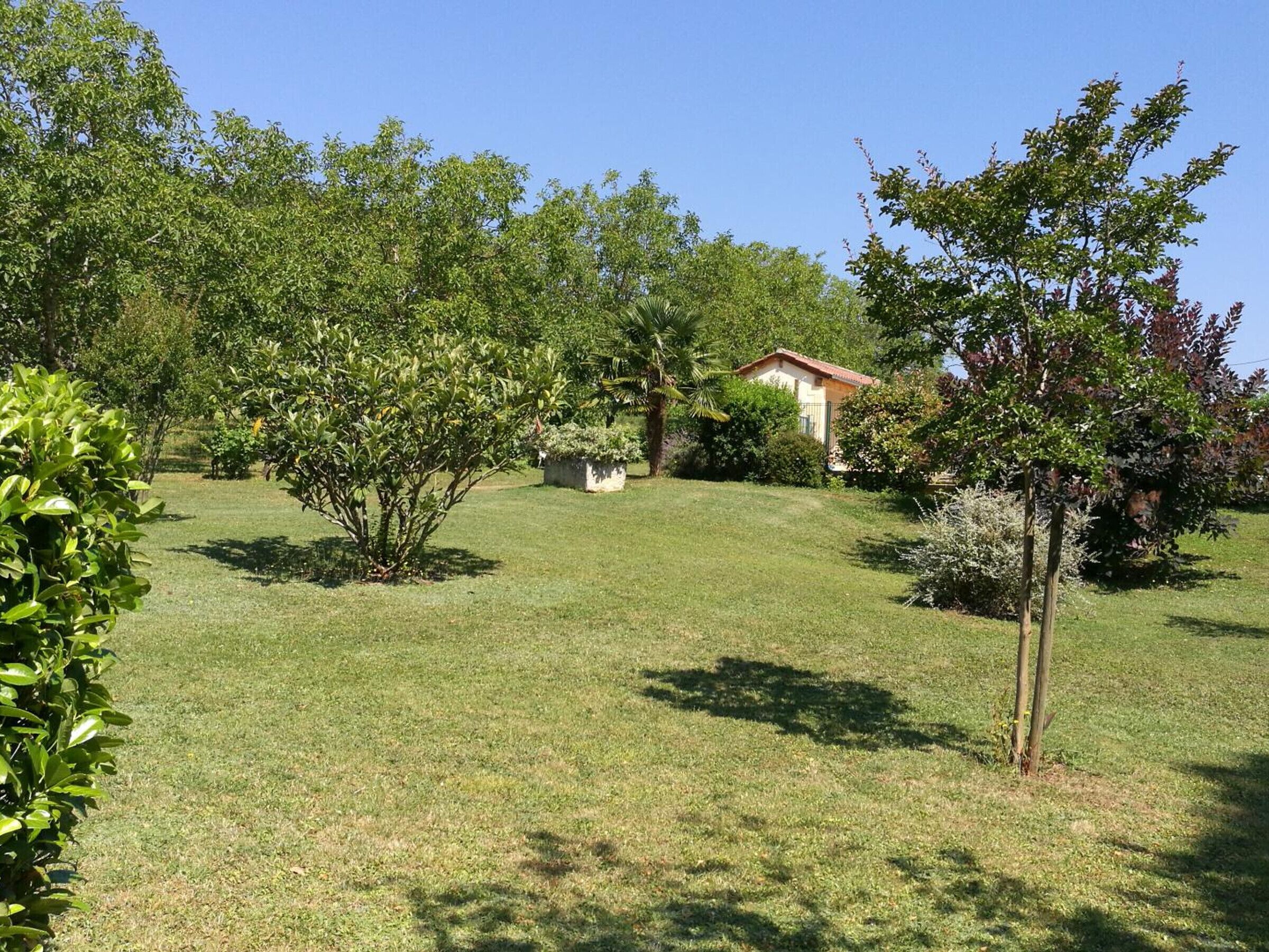 A well-maintained grassy area with trees and a small building.