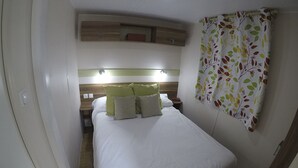 Ett litet hotellrum med ett enda rum, bestående av en säng, ett sängbord och ett litet bord.