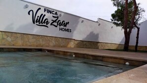 Ett poolområde med en stenmur och en skylt med texten ”FINCA Villa Zaar HOMES”.