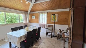 Un comedor con una mesa preparada para cuatro, una silla, una lámpara de pie y un ventanal con cortinas.
