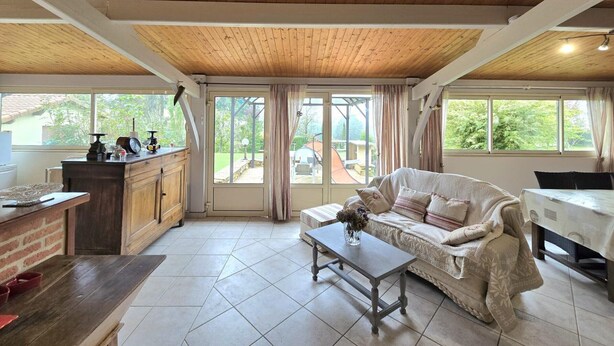 Amplia sala de estar con techo de madera, sofá, mesa de centro y zona de cocina con encimera y armarios.