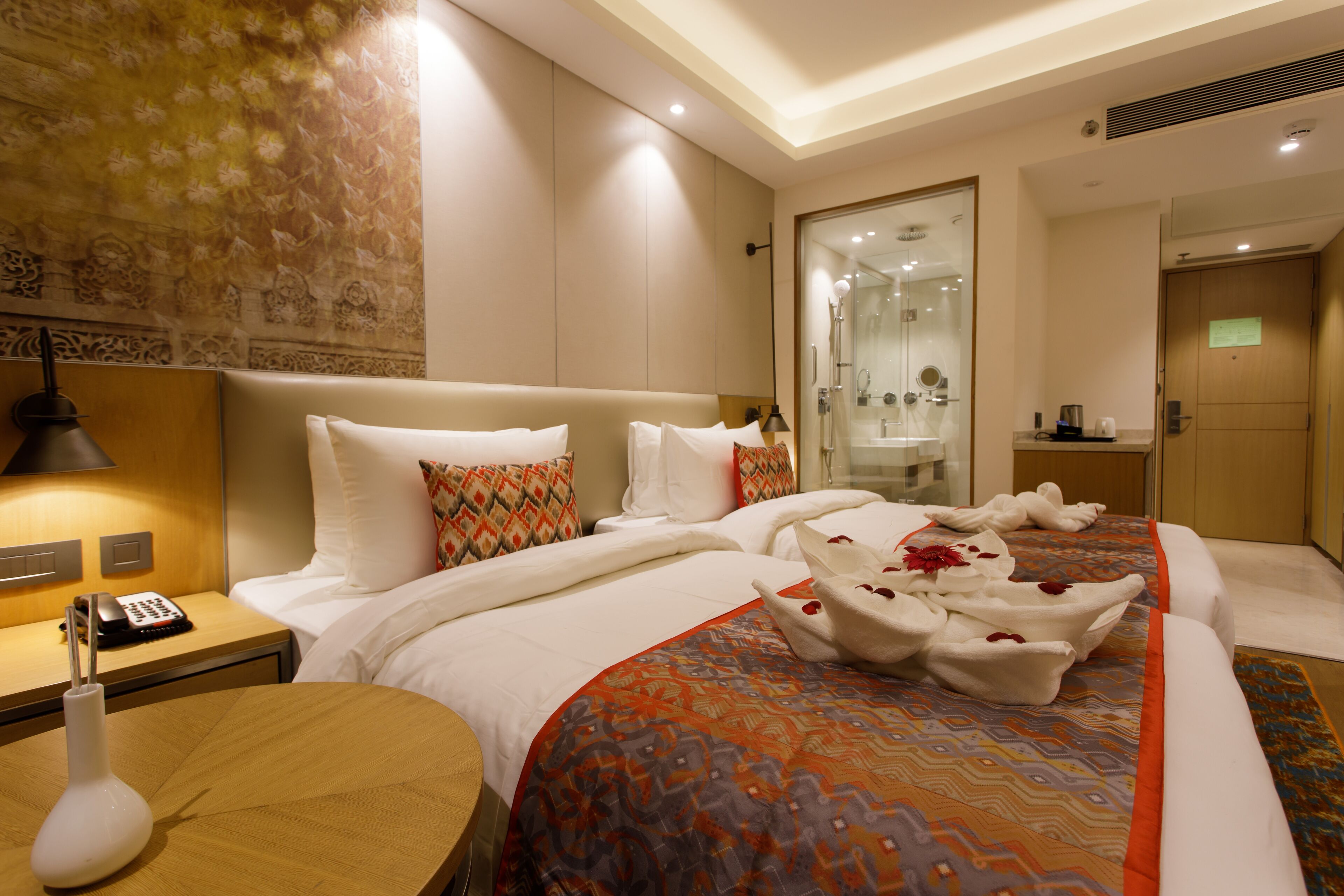 A hotel room with a bed, bedside table, and a mirror.