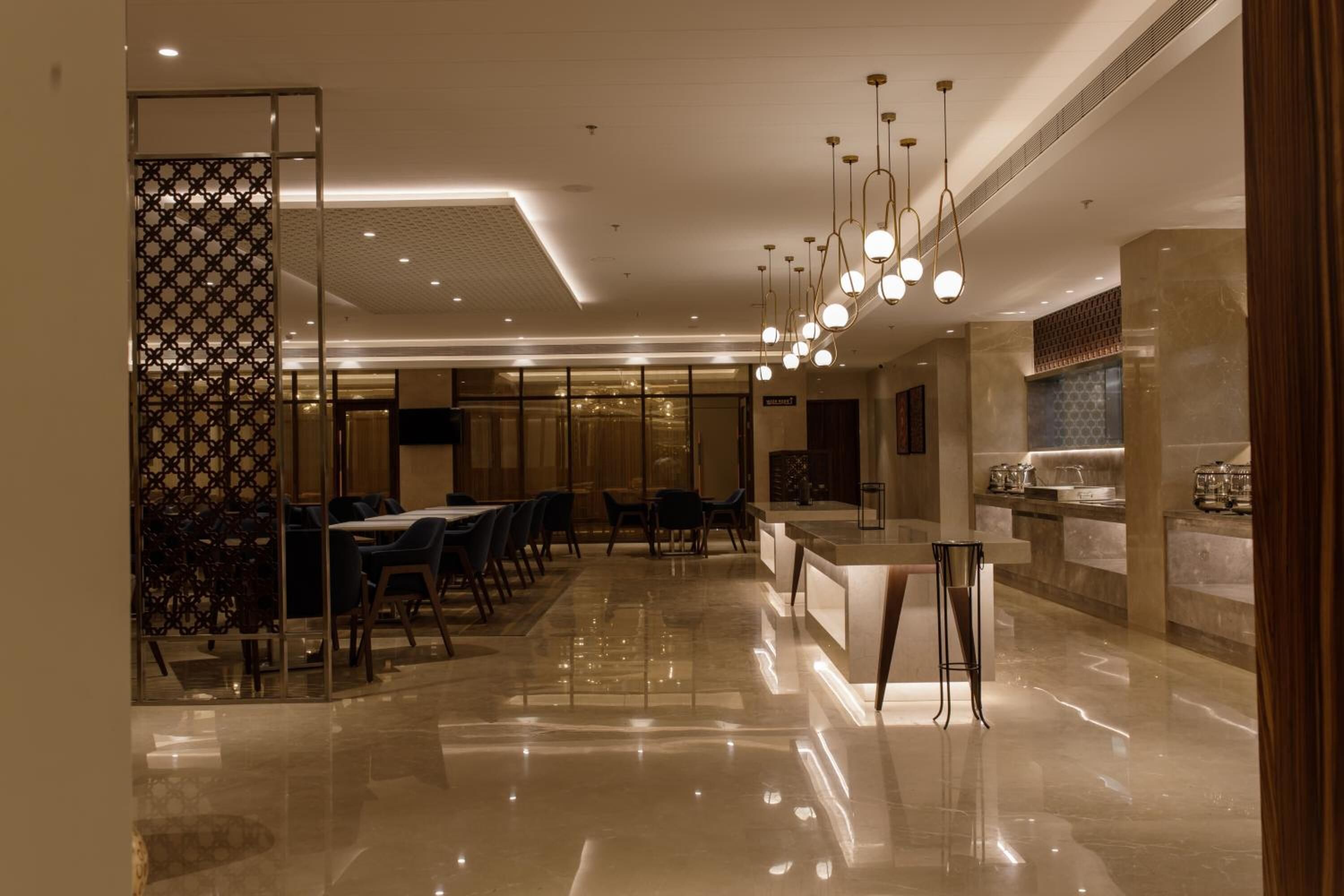 Eine moderne Hotelhalle mit glänzendem Marmorboden, einer Rezeption und einem Essbereich mit Tischen und Stühlen.