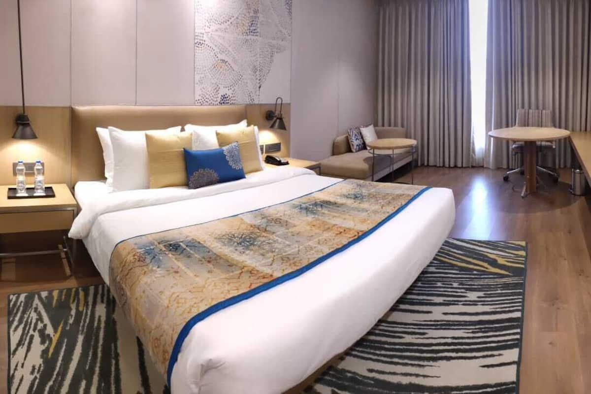 Une chambre d’hôtel moderne avec un grand lit, un bureau, une chaise et une petite table.