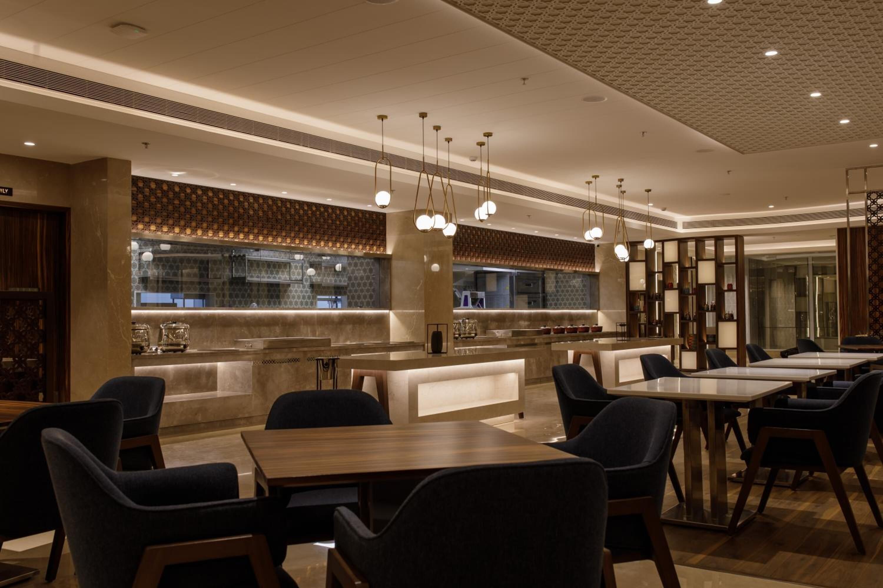 A modern restaurant with a central bar area, multiple seating options, and contemporary lighting fixtures.