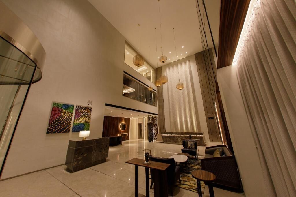 A spacious lobby with a reception desk, seating area, and artwork on the walls.