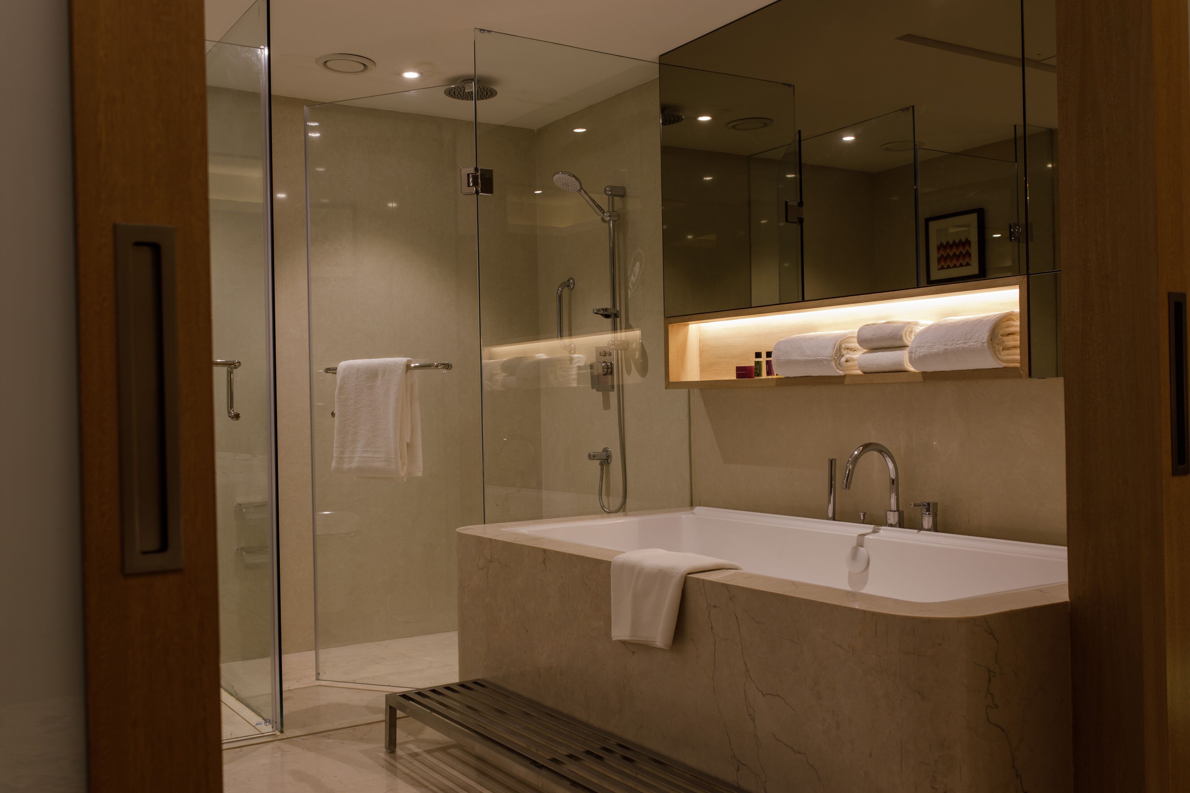 A modern bathroom with a glass-enclosed shower, a freestanding bathtub, and a vanity with a mirror above.