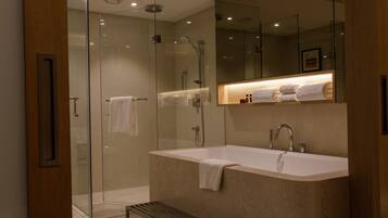 A modern bathroom with a glass-enclosed shower, a freestanding bathtub, and a vanity with a mirror above.