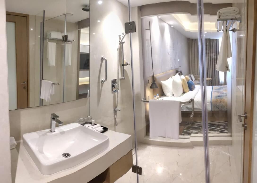 Un baño moderno con ducha de vidrio, un lavamanos blanco y un espejo grande.