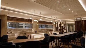 Un interior de restaurante moderno con zona de bar, disposición de mesas y lámparas colgantes.