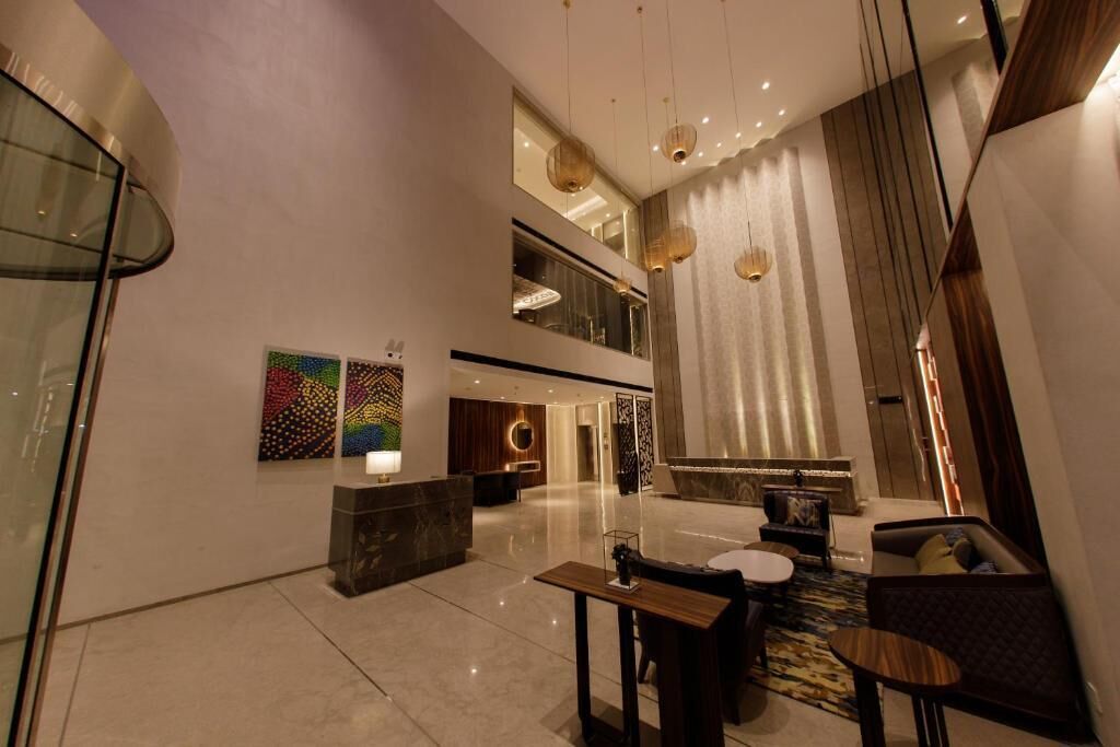 A modern hotel lobby with a reception desk, seating area, and artwork on the walls.